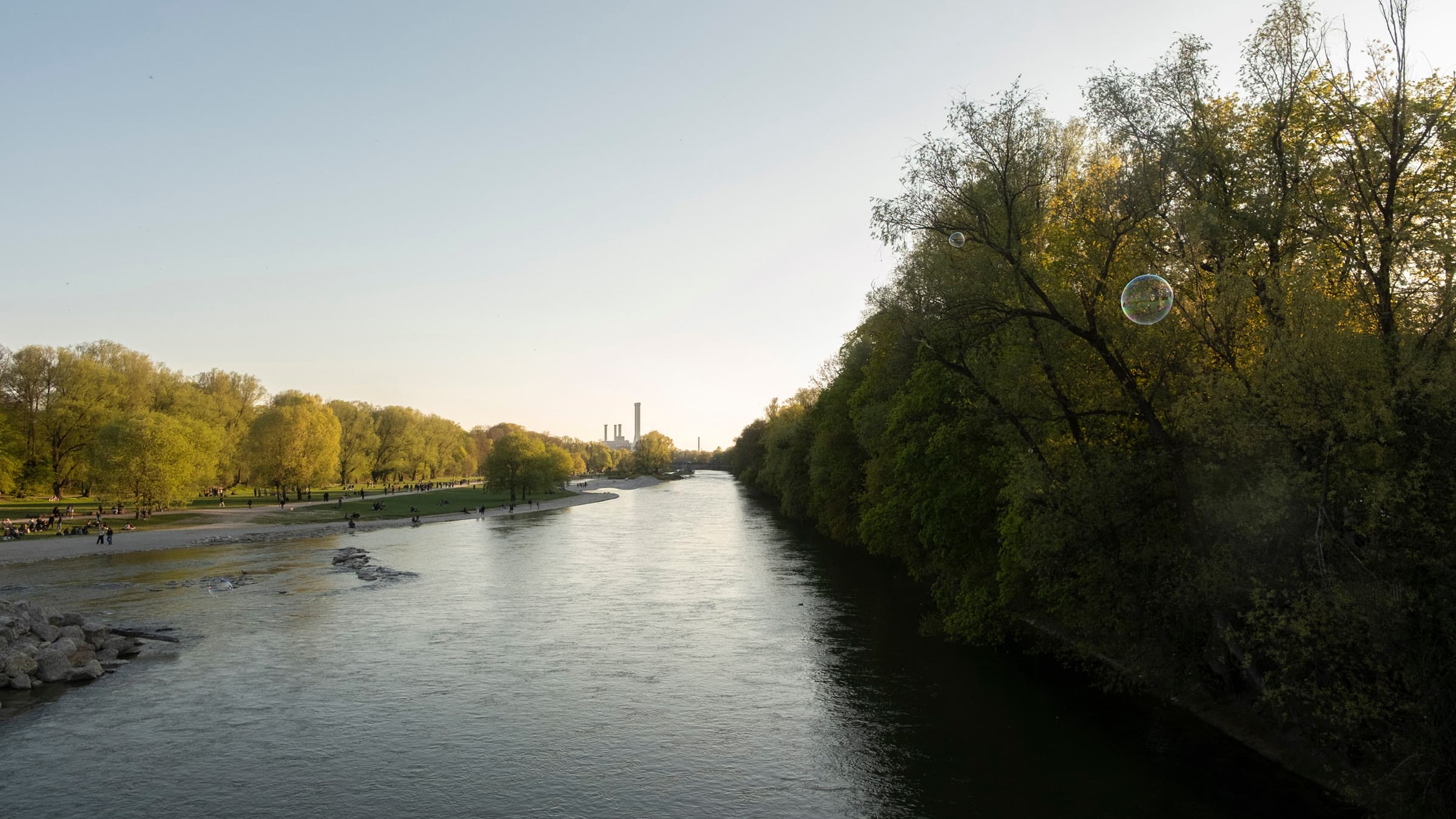 Die Isar im Abendlicht, gesäumt von herbstlich gefärbten Auwäldern