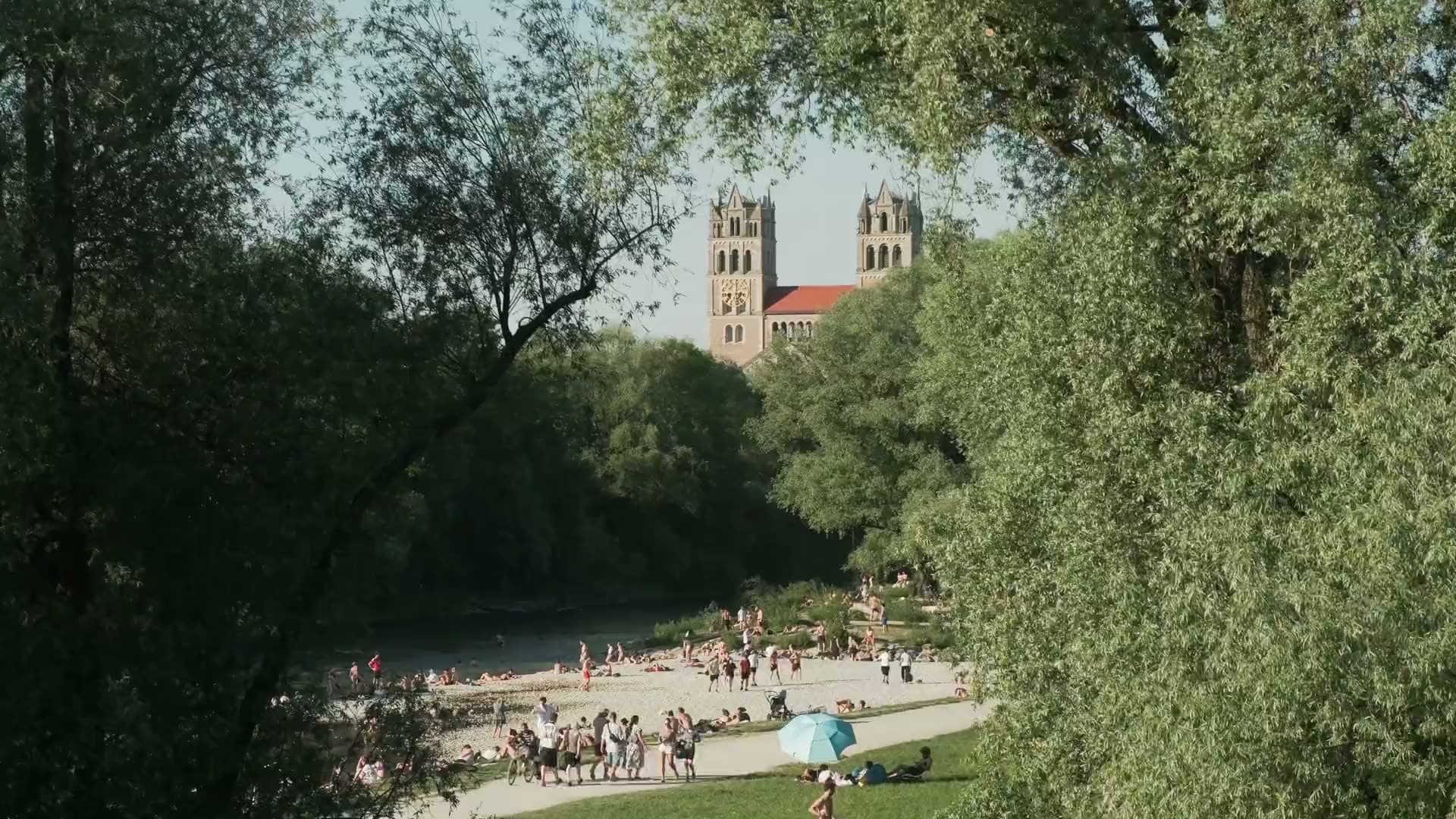 Kiesbank an der Isar mit Badenden, dahinter die Türme von St. Maximilian