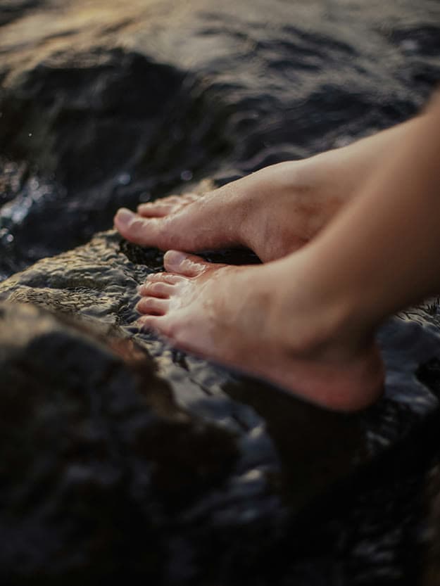 Füße auf einem vom Wasser umspülten Stein