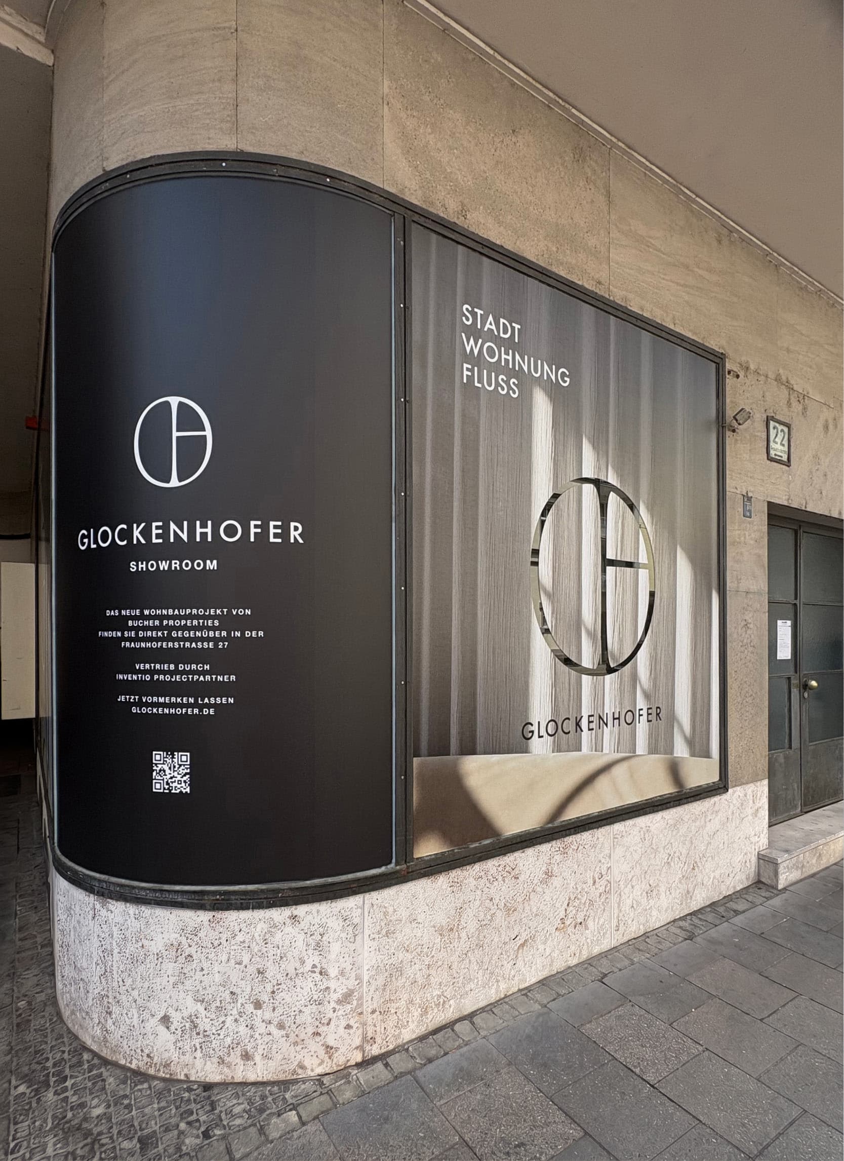 Schaufenster des Glockenhofer-Showrooms mit Bildmarke, Wortmarke und dem Schriftzug Stadt, Wohnung, Fluss