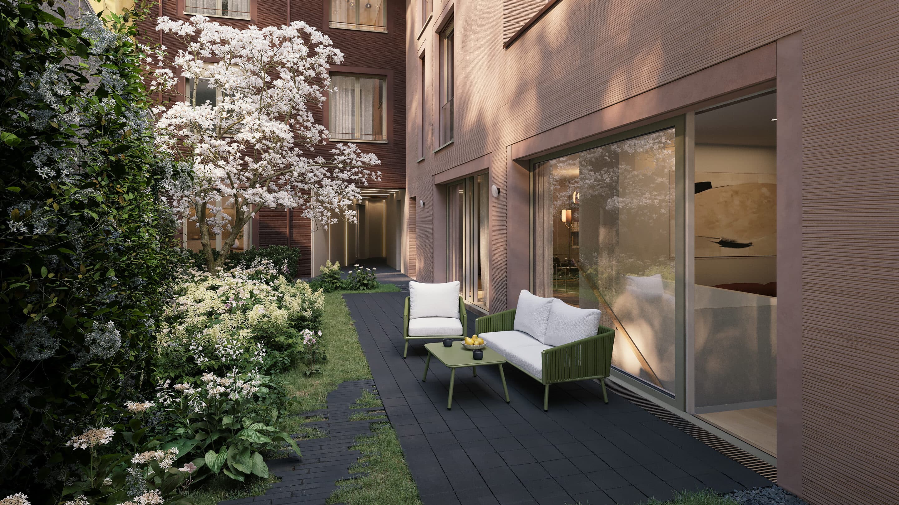 Private Terrasse am begrünten Innenhof, davor eine blühende Magnolie vor der Ziegelfassade